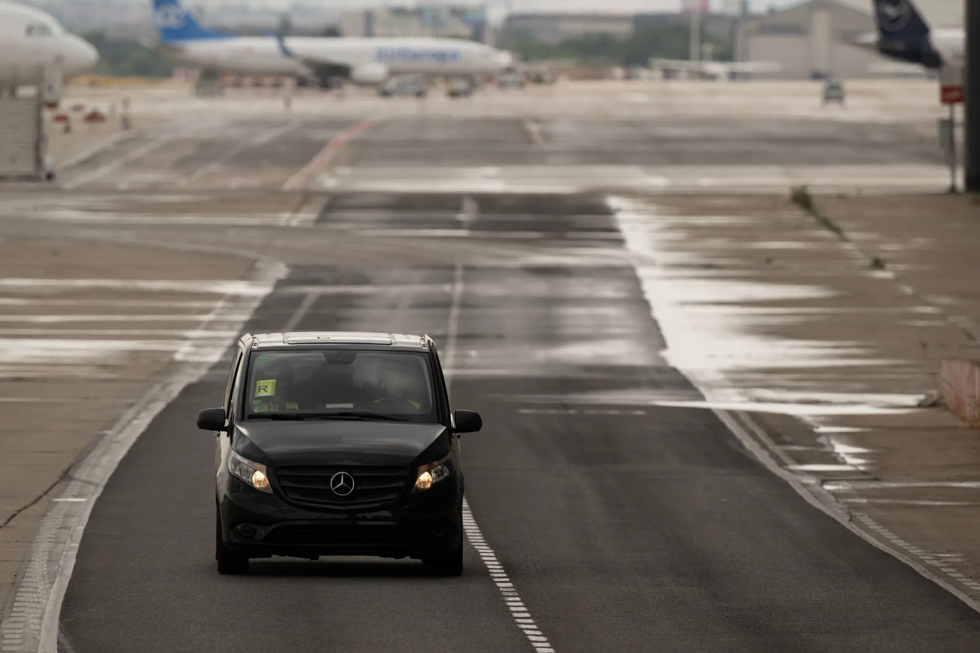 Van noir stationné devant un terminal d'aéroport