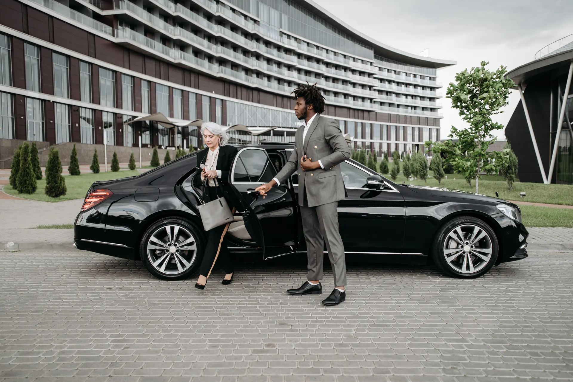 Chauffeur en costume devant un véhicule noir